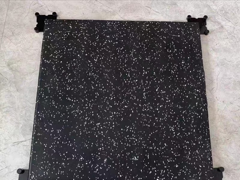 An Olympic weightlifting platform with a wooden center and thick black rubber tiles.